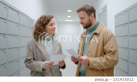 Couple reading documents in hallway with mailboxes in modern apartment building 131433012