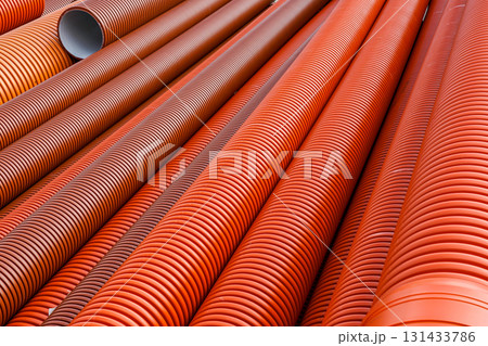 Stack of orange corrugated plastic pipes for drainage, sewage, and construction infrastructure Stack of orange corrugated plastic pipes for drainage, sewage, and construction infrastructure 131433786