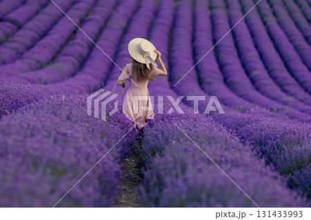 A woman is walking through a field of purple flowers 131433993