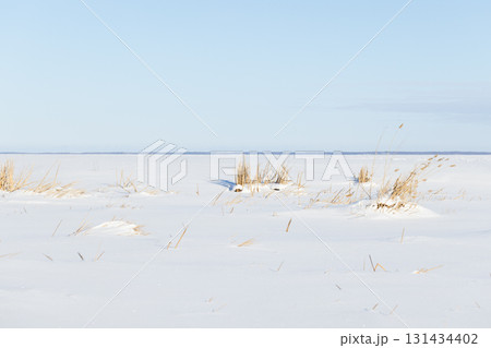 A tranquil winter scene features a flat, snow-covered frozen sea surface 131434402