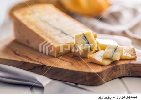 Morbier cheese. Delicious french cheese with mold on cutting board on white table. 131434444