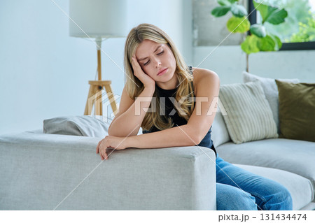 Unhappy upset young woman having headache, sitting on sofa at home Unhappy upset young woman having headache, sitting on sofa at home 131434474