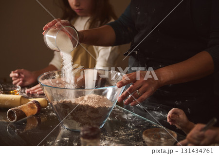 Family Baking Together: Pouring Sugar and Mixing Dough in a Cozy Kitchen Scene Family Baking Together: Pouring Sugar and Mixing Dough in a Cozy Kitchen Scene 131434761