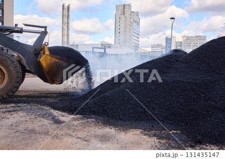 Heavy Machinery Loading Black Aggregate Material at the Construction Site for Development 131435147