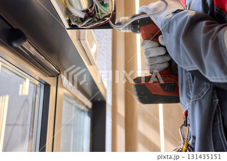An Electrician Skillfully Installing Electrical Components Using a Power Drill Tool 131435151
