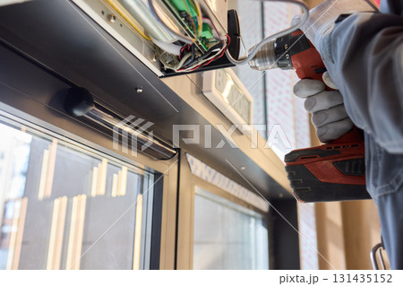 An Electrician Skillfully Installing Electrical Components Using a Power Drill Tool 131435152