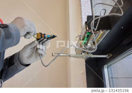 A technician is repairing an advanced automated door system with electrical tools 131435156