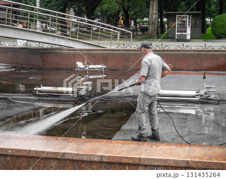 Empty fountain in a city park. Dehumidification. Cleaning the fountain with a hose. The device of the fountain. Pipes for water supply. Water hoses. Modern technologies. Infrastructure maintenance. 131435264