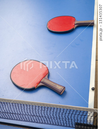 Ping pong tables in the park. Table tennis rackets on a table in the park. The concept of the end of the game. holiday at the resort Ping pong tables in the park. Table tennis rackets on a table in the park. The concept of the end of the game. holiday at the resort 131435307
