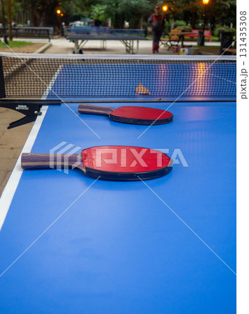 Ping pong tables in the park. Table tennis rackets on a table in the park. The concept of the end of the game. holiday at the resort. Ping pong tables in the park. Table tennis rackets on a table in the park. The concept of the end of the game. holiday at the resort. 131435308