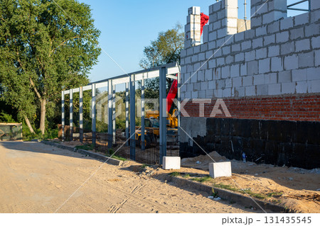 Building under construction at construction site with telescopic crane and loader in the background. Building under construction at construction site with telescopic crane and loader in the background. 131435545