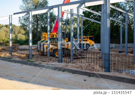 Telescopic handlers and a mobile crane at a construction site in the evening in the rays Telescopic handlers and a mobile crane at a construction site in the evening in the rays 131435547