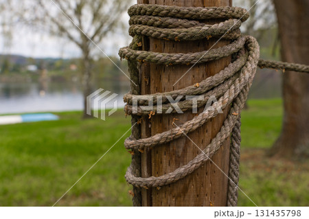 Closeup of weathered rope wrapped around wooden post by lake in Nova Zivohost, Czech Republic. Closeup of weathered rope wrapped around wooden post by lake in Nova Zivohost, Czech Republic. 131435798