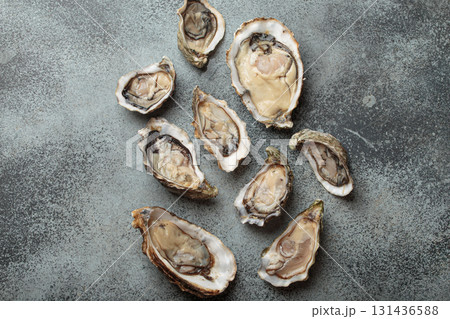 Fresh opened oysters scattered on dark gray surface top view 131436588