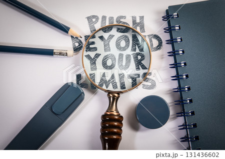 Push Beyond Your Limits Motivation Message with Magnifying Glass and Office Supplies on Desk 131436602