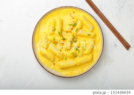 Traditional korean tteokbokki in creamy cheese sauce with garnish, wooden chopsticks on rustic white background top view 131436634