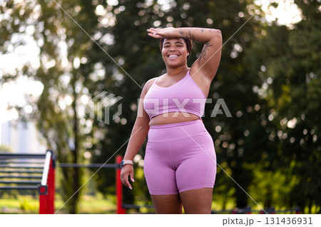 Plus size young woman in pink top and shorts feeling tired after workout 131436931