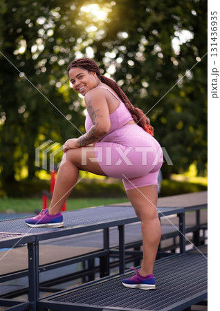 Young woman in pink sportswear exercising at the sports ground Young woman in pink sportswear exercising at the sports ground 131436935