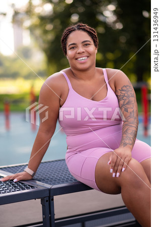 Young smiling woman in pink sportswear resting after a workout 131436949