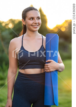 Cute young girl with a yoga mat walking in the park Cute young girl with a yoga mat walking in the park 131436989