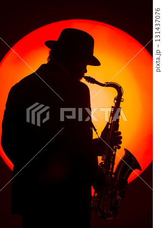 silhouette of saxophone player with orange backdrop 131437076
