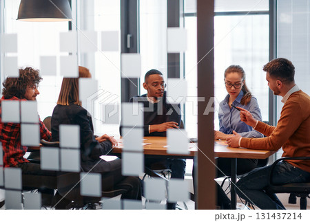 In a sleek glass office space, a team of business professionals engage in lively discussions and exchange strategic ideas, showcasing collaboration and innovation at the heart of modern corporate In a sleek glass office space, a team of business professionals engage in lively discussions and exchange strategic ideas, showcasing collaboration and innovation at the heart of modern corporate 131437214