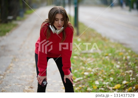 Athletic young woman taking a breath and relaxing after jogging and stretching. Woman Training and Workout Exercises On Street. Athletic young woman taking a breath and relaxing after jogging and stretching. Woman Training and Workout Exercises On Street. 131437329