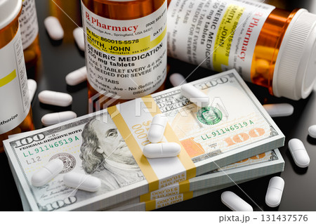 Prescription Medicine Bottles and Pills Next To Stacks of 100 Dollar Bills. 131437576