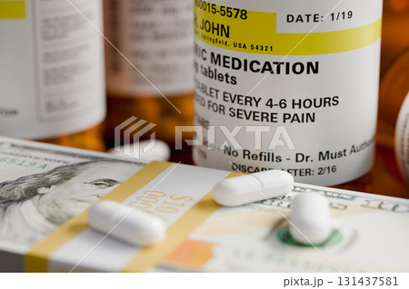 Prescription Medicine Bottles and Pills Next To Stacks of 100 Dollar Bills. 131437581