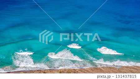 Blue ocean with waves and a sandy beach, top view. 131437815