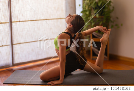 Young girl stretching in serene indoor space. Blurred background. Natural light 131438162