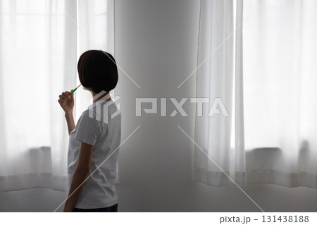 窓辺で歯磨きをするミドル女性 131438188