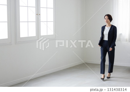 屋内を歩くミドル世代のスーツ姿の女性 131438314