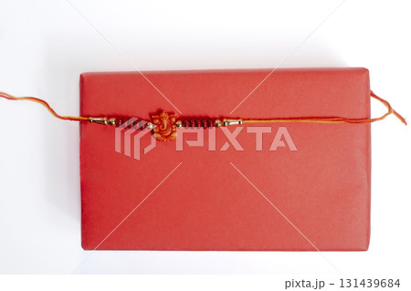 Red gift box with a soft beaded bracelet wrapped in orange thread for gift giving on Raksha Bandhan. 131439684
