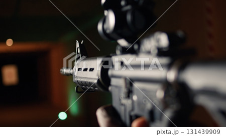Shooting gallery client hitting paper targets with ammo, extreme close up of rifle. Close up of person at firing range establishment shooting bullseyes, enjoying using semiautomatic weapon, camera A Shooting gallery client hitting paper targets with ammo, extreme close up of rifle. Close up of person at firing range establishment shooting bullseyes, enjoying using semiautomatic weapon, camera A 131439909