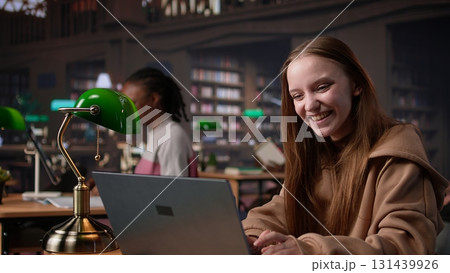 Diverse classmates sharing high five and feeling happy with their success, finishing school assignment in time and expecting a high grade. Girls doing amazing teamwork at the library. Camera B. Diverse classmates sharing high five and feeling happy with their success, finishing school assignment in time and expecting a high grade. Girls doing amazing teamwork at the library. Camera B. 131439926