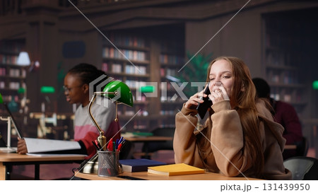 Noisy girl disturbing students at the library by speaking very loud on call, being rude and answering her phone in the study area. Disruptive annoying person asked to keep silence. Camera A. Noisy girl disturbing students at the library by speaking very loud on call, being rude and answering her phone in the study area. Disruptive annoying person asked to keep silence. Camera A. 131439950