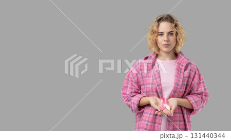 Woman in pink displays a cancer awareness ribbon Woman in pink displays a cancer awareness ribbon 131440344