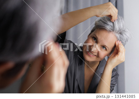 An adult well-groomed beautiful woman of age during menopause with gray hair examines the amount 131441085