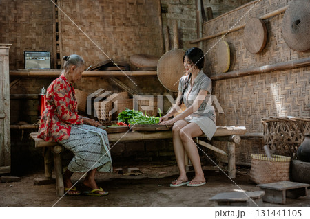 Cultural Exchange: Traditional Villager and Young Woman Share Local Harvest Cultural Exchange: Traditional Villager and Young Woman Share Local Harvest 131441105
