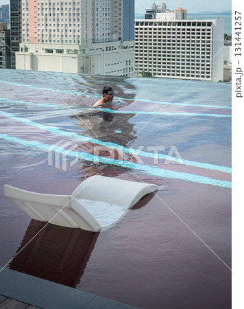 Man swimming in infinity roof top pool. Man swimming in infinity roof top pool. 131441257