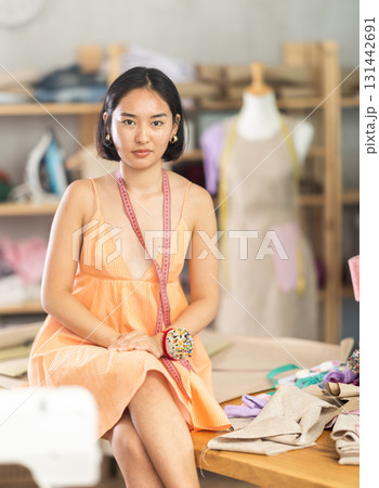 Portrait of positive girl tailor in sewing workshop 131442691