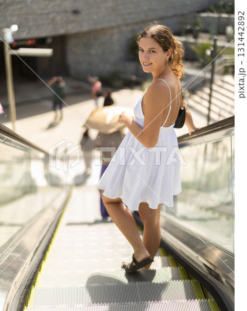 Woman standing on escalator on a sunny day Woman standing on escalator on a sunny day 131442892