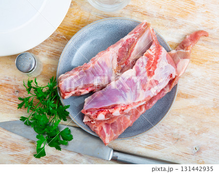 Raw meaty pork ribs slabs on plate with fresh greens Raw meaty pork ribs slabs on plate with fresh greens 131442935