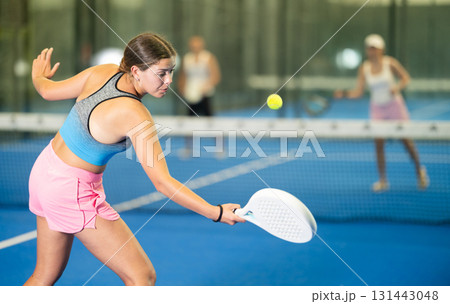 Young woman playing tennis against man and woman 131443048