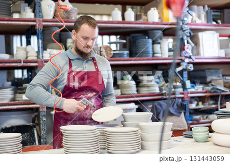Young man paints blanks of ceramic products 131443059