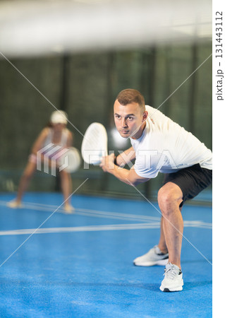 Young man and adult woman playing doubles tennis Young man and adult woman playing doubles tennis 131443112