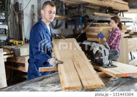 Young man puts oak plank on table 131443304