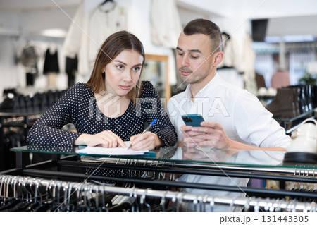 Man with phone in hands participates in discussion of business development plans with wife Man with phone in hands participates in discussion of business development plans with wife 131443305