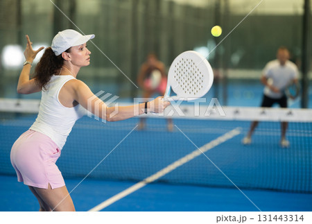 Adult woman playing tennis against man and woman 131443314